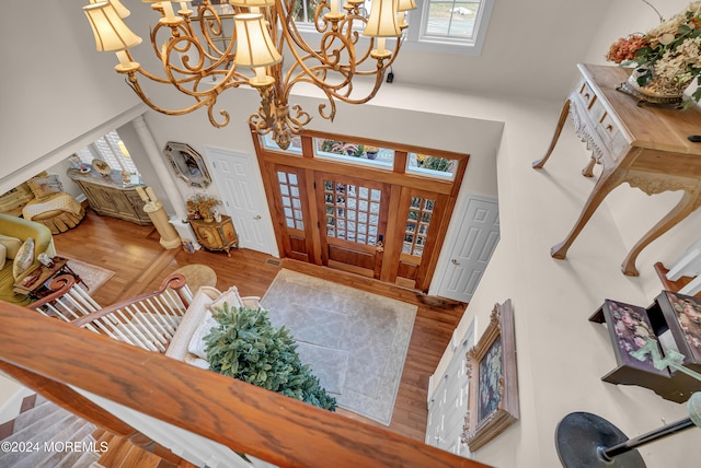 foyer with hardwood / wood-style floors, ornate columns, and an inviting chandelier