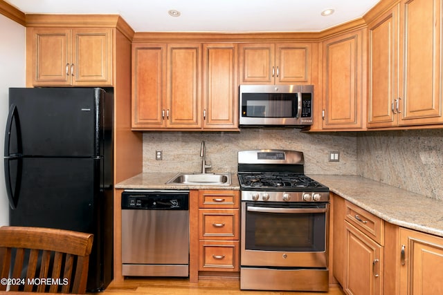 kitchen featuring light wood-type flooring, appliances with stainless steel finishes, sink, and decorative backsplash