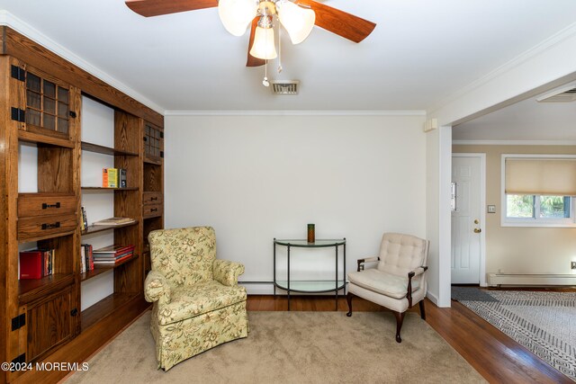 sitting room with ceiling fan, hardwood / wood-style flooring, baseboard heating, and ornamental molding