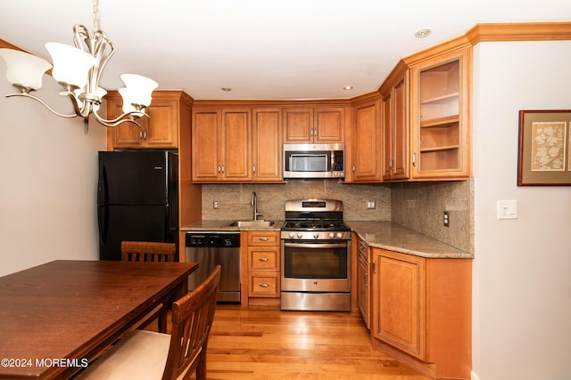 kitchen with stainless steel appliances, light hardwood / wood-style floors, tasteful backsplash, light stone countertops, and pendant lighting