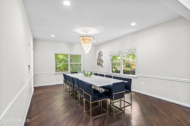 dining room with a wealth of natural light, dark hardwood / wood-style floors, and an inviting chandelier