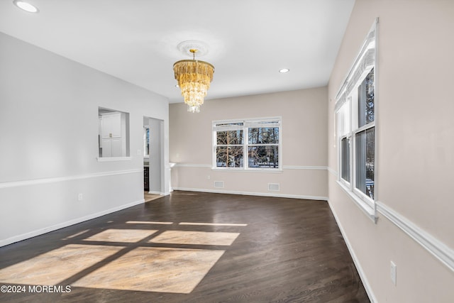 spare room with dark hardwood / wood-style floors and a chandelier