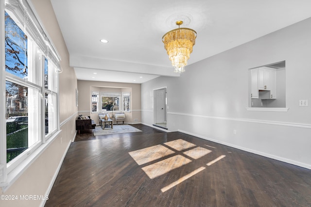 unfurnished living room with dark wood-type flooring and an inviting chandelier