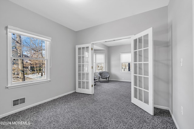 empty room featuring dark colored carpet and french doors