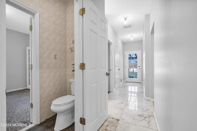 bathroom with tile walls and toilet