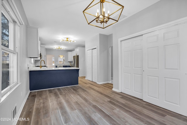 kitchen featuring white cabinets, kitchen peninsula, wood-type flooring, and pendant lighting