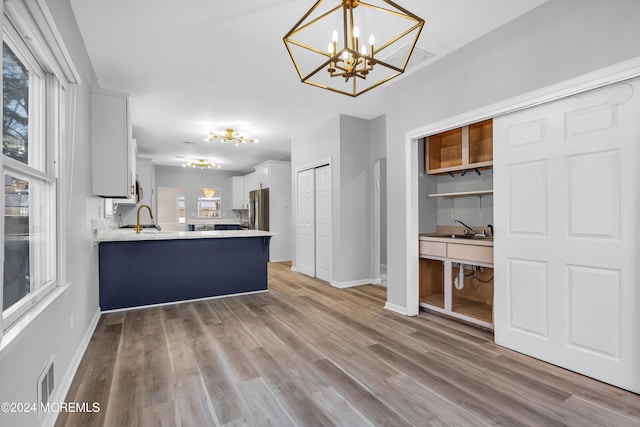 kitchen with wood-type flooring, white cabinetry, decorative light fixtures, and kitchen peninsula