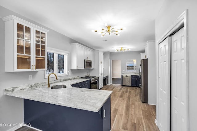 kitchen with stainless steel appliances, light hardwood / wood-style floors, white cabinetry, sink, and kitchen peninsula