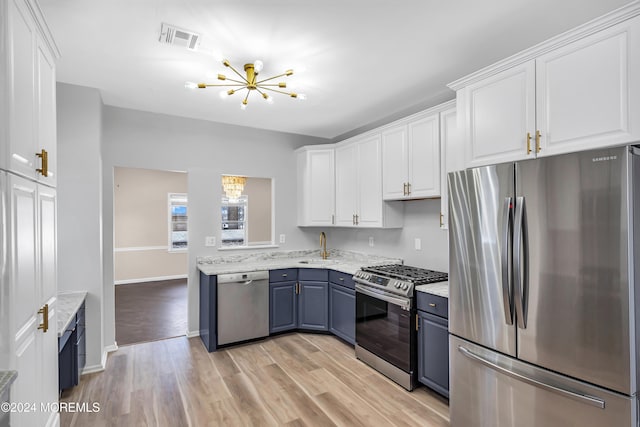 kitchen with white cabinetry, light hardwood / wood-style flooring, appliances with stainless steel finishes, and a notable chandelier