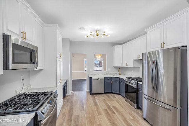 kitchen featuring stainless steel appliances, white cabinetry, light stone countertops, sink, and light hardwood / wood-style flooring