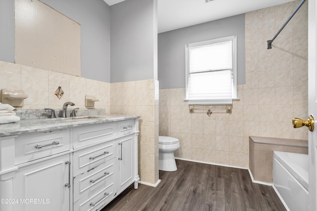 full bathroom with hardwood / wood-style flooring, tile walls, vanity, toilet, and shower / bathtub combination