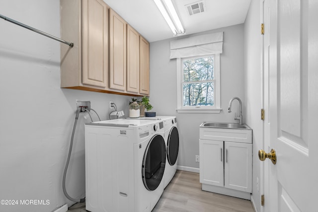 clothes washing area with cabinets, sink, light hardwood / wood-style flooring, and independent washer and dryer