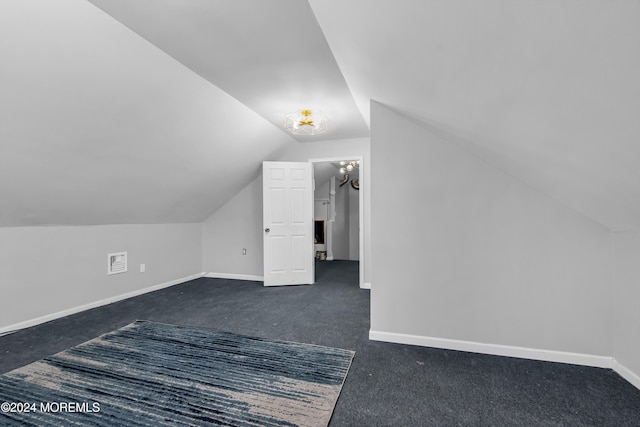 additional living space with vaulted ceiling and dark colored carpet