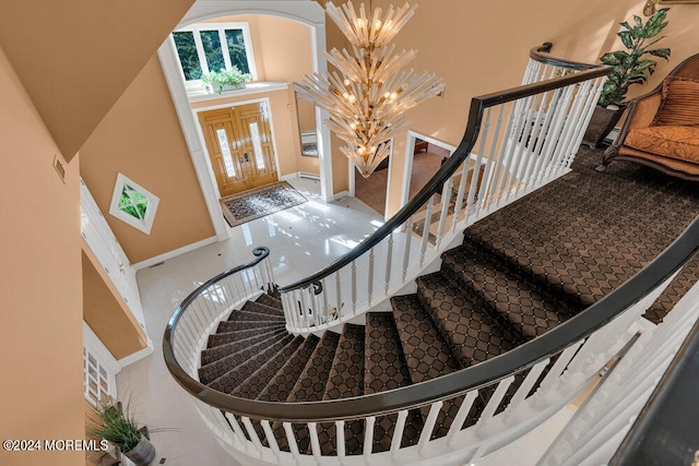 stairway with a towering ceiling and a chandelier