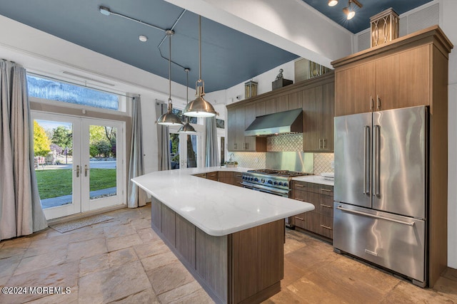 kitchen with tasteful backsplash, french doors, wall chimney range hood, decorative light fixtures, and high quality appliances