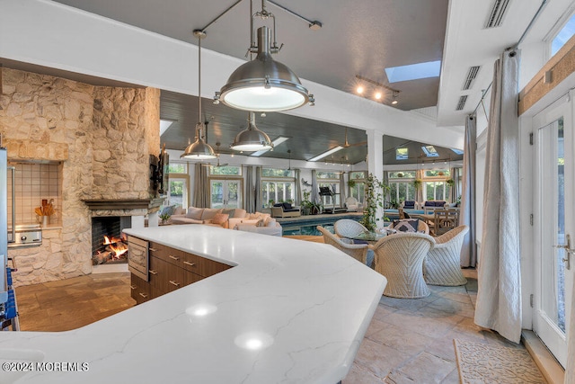 kitchen featuring light stone countertops, a wealth of natural light, decorative light fixtures, and a fireplace