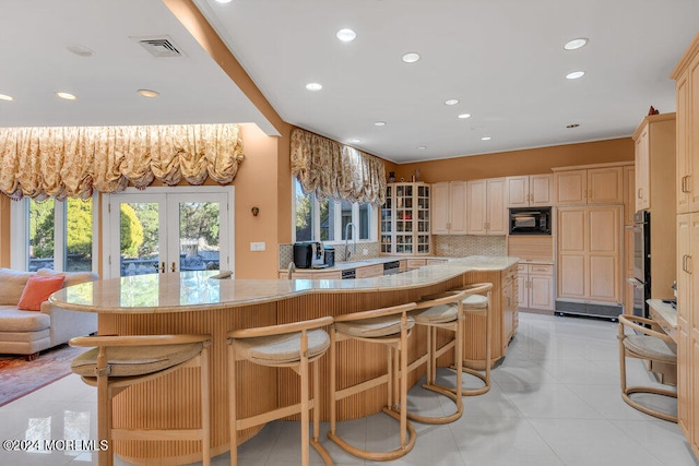 kitchen with backsplash, a breakfast bar area, french doors, and black microwave