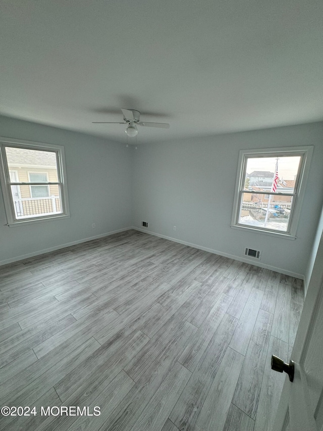 spare room featuring ceiling fan, light hardwood / wood-style floors, and a healthy amount of sunlight