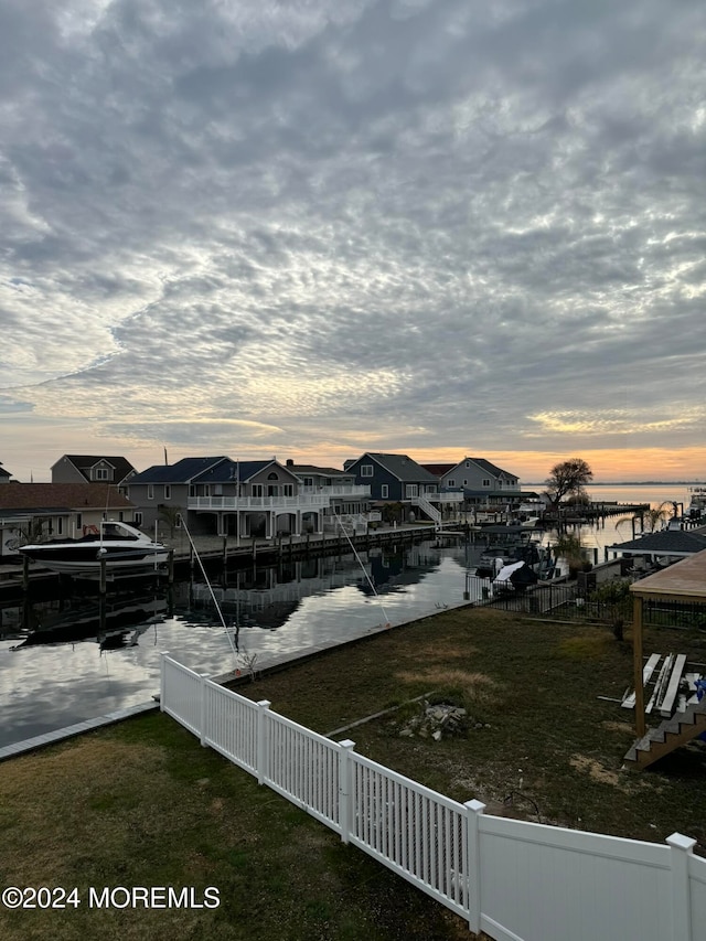 view of dock with a lawn and a water view