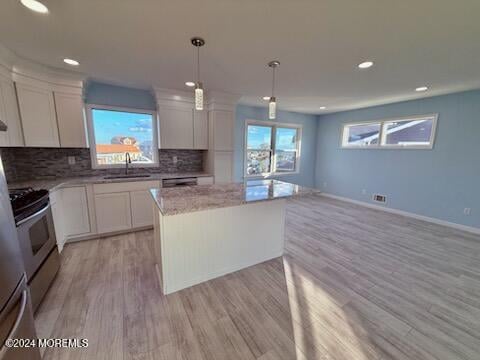 kitchen featuring light hardwood / wood-style floors, a center island, white cabinets, hanging light fixtures, and backsplash