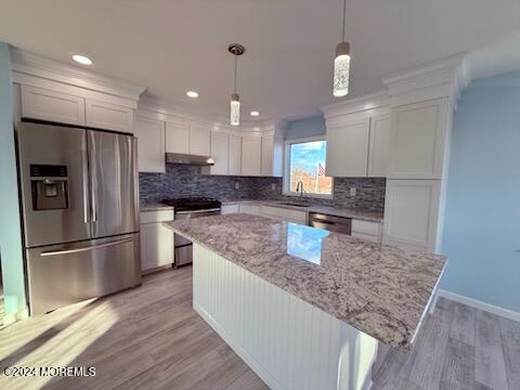 kitchen featuring light hardwood / wood-style floors, decorative backsplash, a kitchen island, and appliances with stainless steel finishes