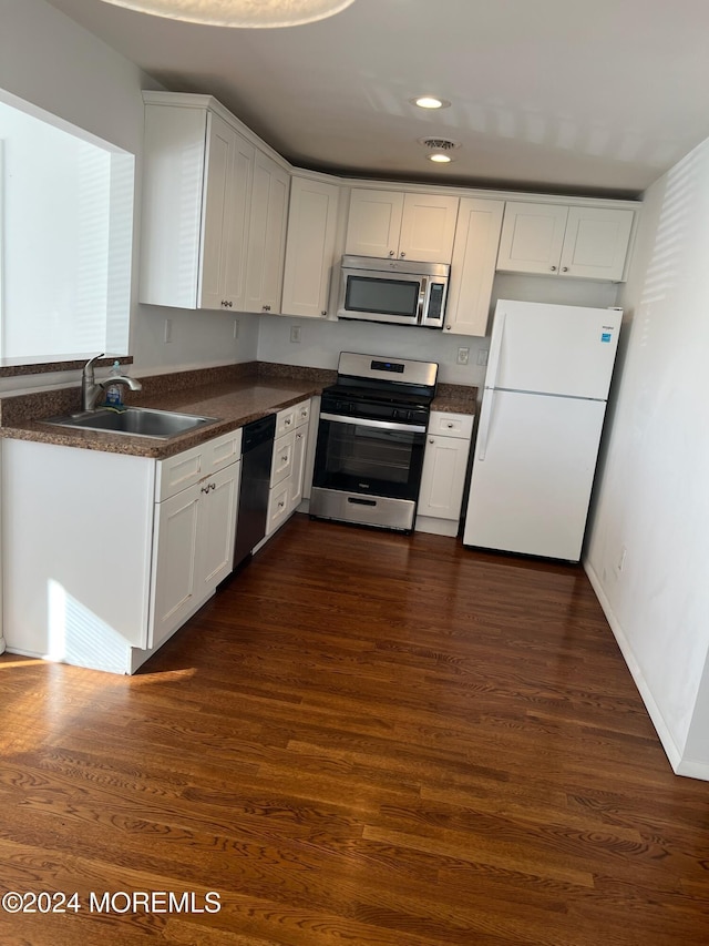 kitchen featuring dark hardwood / wood-style flooring, white cabinetry, sink, and appliances with stainless steel finishes