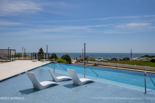 view of swimming pool with a water view and a patio area