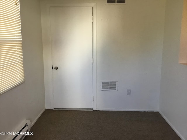 carpeted empty room featuring baseboard heating