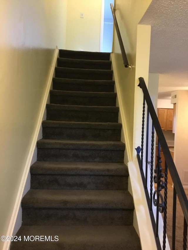 stairs with a textured ceiling