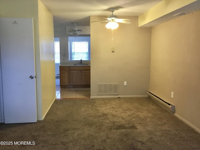 carpeted empty room featuring baseboard heating, ceiling fan, and sink