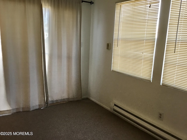 empty room featuring baseboard heating and dark colored carpet