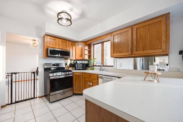 kitchen featuring stainless steel appliances, light tile patterned floors, an inviting chandelier, sink, and kitchen peninsula