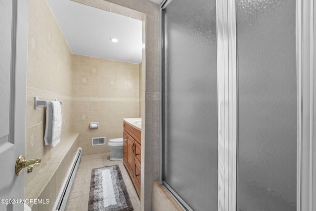 bathroom featuring tile patterned floors, vanity, baseboard heating, tile walls, and toilet