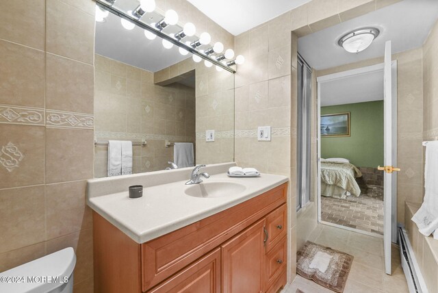 bathroom with vanity, tile patterned flooring, toilet, tile walls, and a baseboard radiator