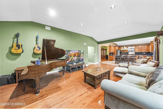 living room featuring light wood-type flooring, lofted ceiling, and a chandelier