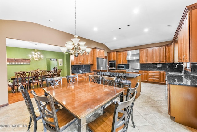 dining space featuring a chandelier, light tile patterned flooring, sink, and vaulted ceiling