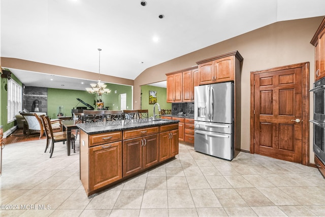 kitchen with a center island, stainless steel appliances, dark stone countertops, decorative light fixtures, and lofted ceiling