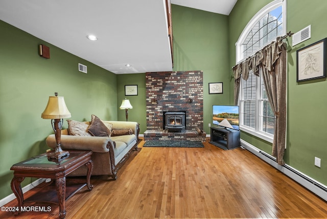 living room with a wood stove, baseboard heating, and light hardwood / wood-style flooring