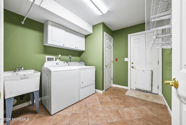 clothes washing area with washer and clothes dryer, cabinets, and light tile patterned floors