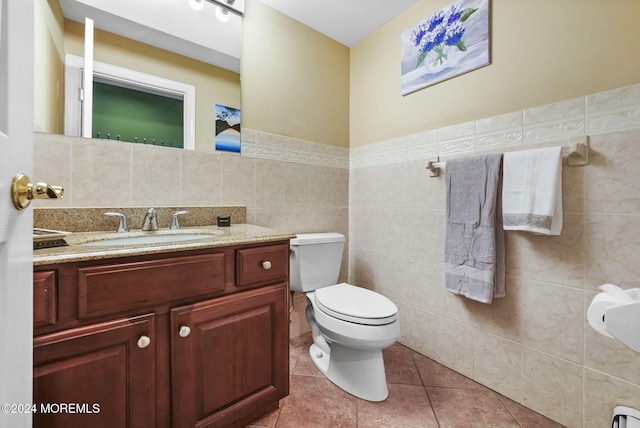 bathroom featuring toilet, vanity, tile patterned floors, and tile walls