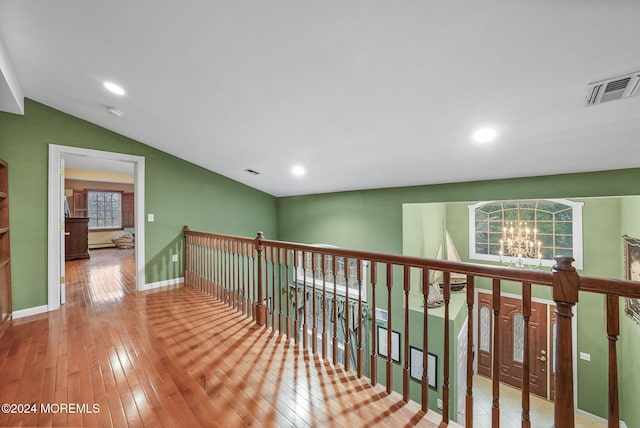 corridor featuring an inviting chandelier, light hardwood / wood-style flooring, vaulted ceiling, and baseboard heating