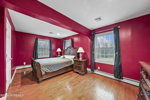 bedroom featuring hardwood / wood-style floors and a baseboard heating unit