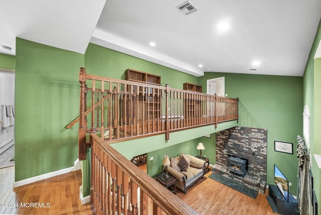 interior space featuring hardwood / wood-style floors, lofted ceiling, a wood stove, and a baseboard radiator