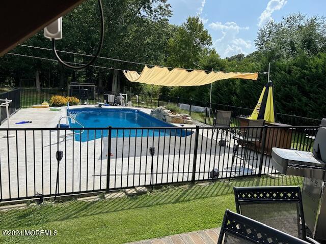 view of swimming pool featuring a patio area and a yard