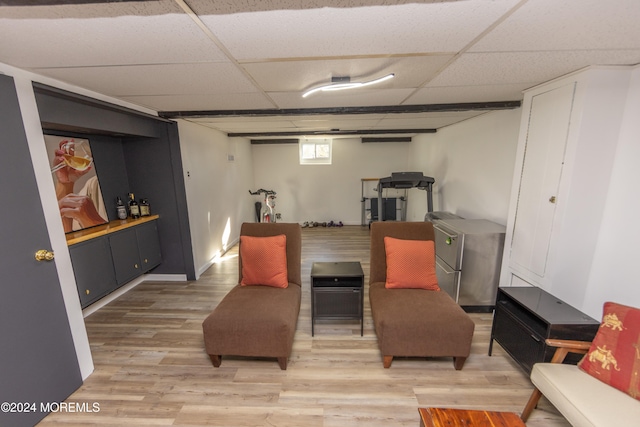 living area with a drop ceiling and wood-type flooring