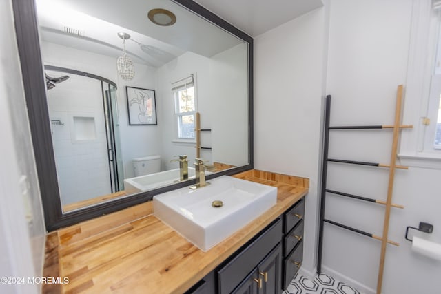 bathroom featuring vanity, a chandelier, toilet, and a shower with shower door