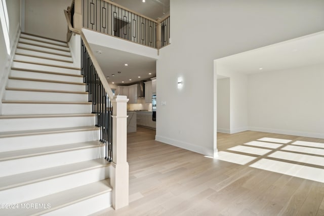 stairway with wood-type flooring and a towering ceiling