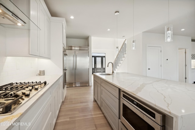 kitchen featuring light stone countertops, white cabinetry, hanging light fixtures, and appliances with stainless steel finishes