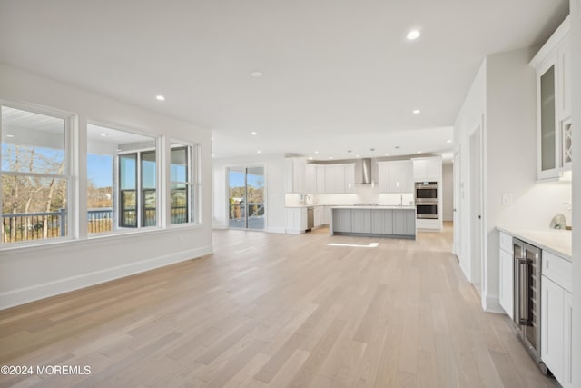 unfurnished living room featuring wine cooler and light hardwood / wood-style floors