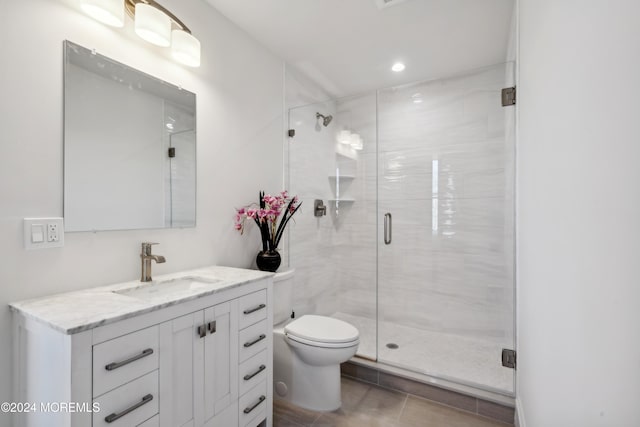 bathroom with tile patterned flooring, vanity, a shower with shower door, and toilet